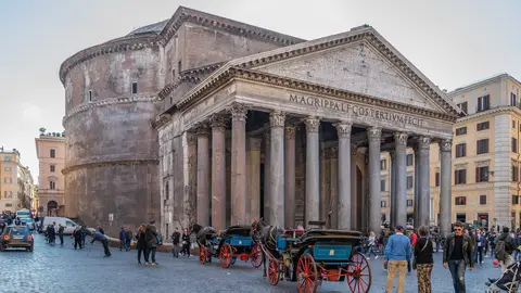 The Pantheon in Rome seen from Piazza della Rotonda, its columned portico and dome above a crowd of walkers and horse carriages